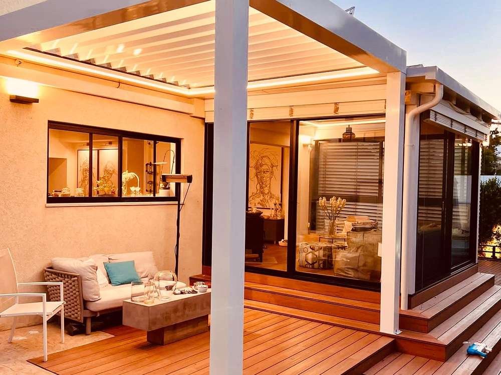 Gün batımında ahşap deck üzerinde beyaz biyoklimatik pergola